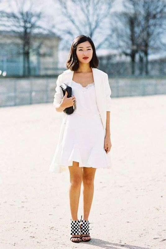 A white A line mini dress with a lace neckline and ruffle skirt, white oversized blazer and checked shoes plus a black bag