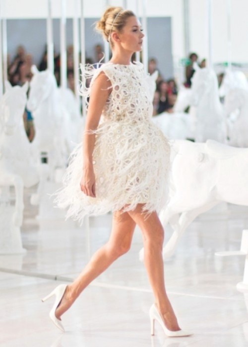 a sleeveless mini dress with feathers all over it plus high white heels for an ultra-modern and super bold look