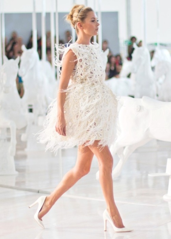 A sleeveless mini dress with feathers all over it plus high white heels for an ultra modern and super bold look