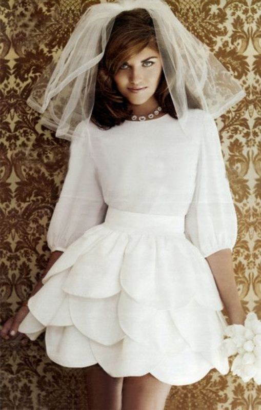 A creative mini wedding dress with a bodice and puff sleeves, a high neckline and a whimsical full scallop layer skirt