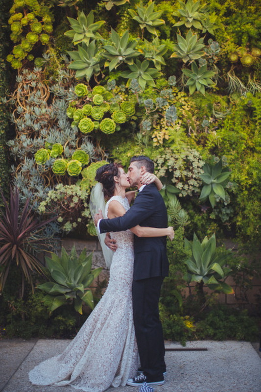 A lush living greenery wall with lots of succulents and statement plants and moss is a gorgeous wedding ceremony backdrop with a modern feel