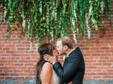 an exposed brick wall is softened with a greenery hanging and looks as a fresh and wild wedding backdrop