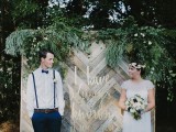 a reclaimed woodchevron wall with lush greenery with various textures is a lovely rustic backdrop for a wedding