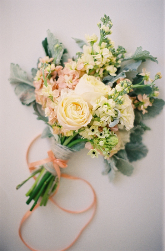 a beautiful and bright yellow and pink wedding bouquet with pale foliage and greenery and coral ribbons is amazing