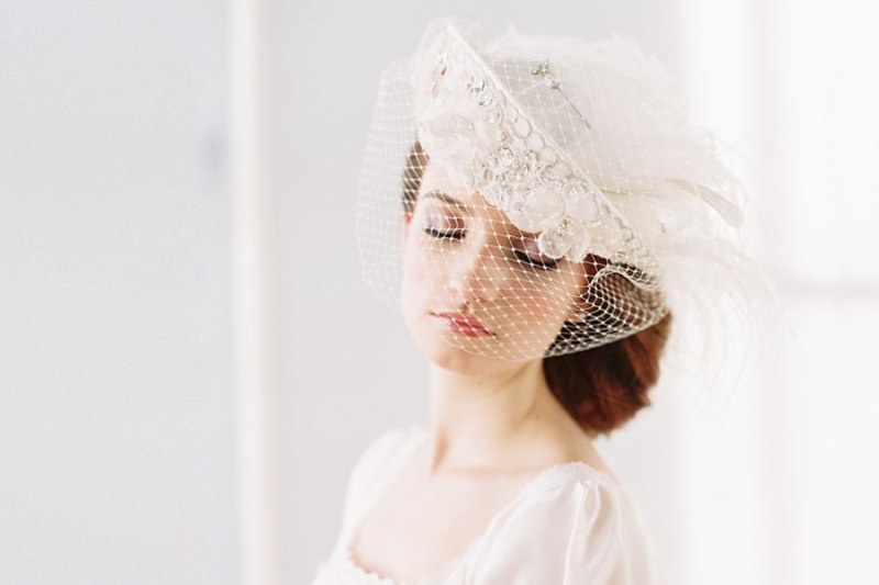 A beautiful vintage bridal hat in white, with a birdcage veil, rhinestones, pearls and feathers is amazing