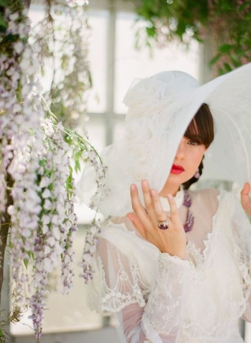a vintage white wide-brim hat with white fabric blooms on top is a gorgeous idea to finish off your bridal look