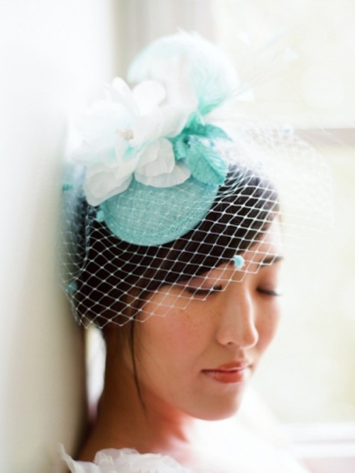 a small and lovely bridal hat in white and mint, with fabric blooms and foliage and a small birdcage veil is amazing