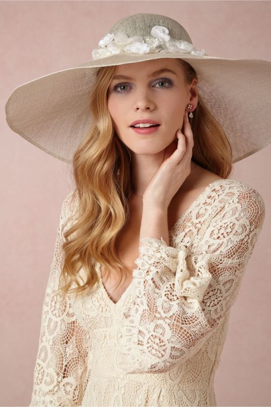A neutral wide brim hat with white fabric blooms on top is a chic and stylish idea for a bride who loves vintage