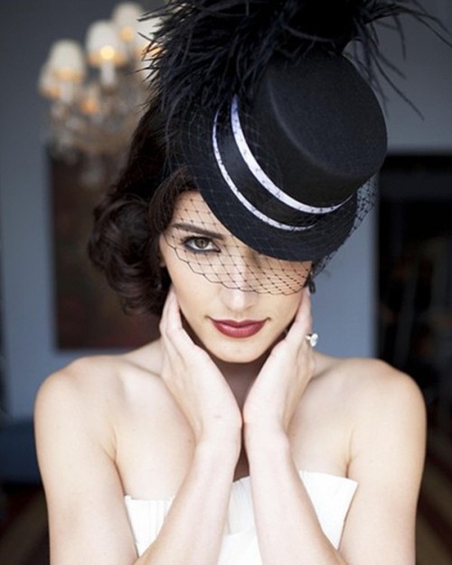 a black mini hat with white ribbon, a birdcage veil and large feathers is a stylish and catchy accessory to rock