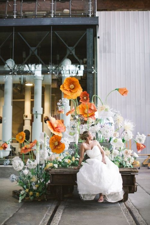 a fantastic spring wedding photo spot with oversized faux blooms of various colors and greenery is a gorgeous idea looking very fresh