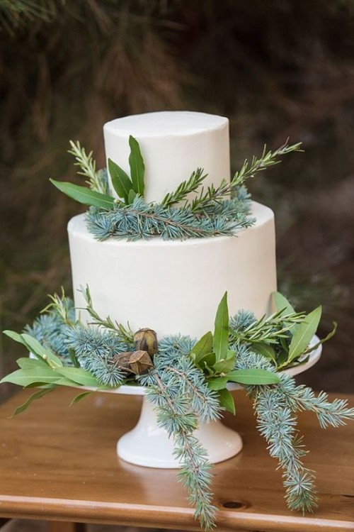 a beautiful wedding cake in white, with gorgeous greenery, branches and even dried elements for a winter or Christmas wedding
