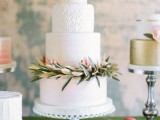 a textural neutral wedding cake with patterns with greenery and bright berries for a Christmas or winter wedding