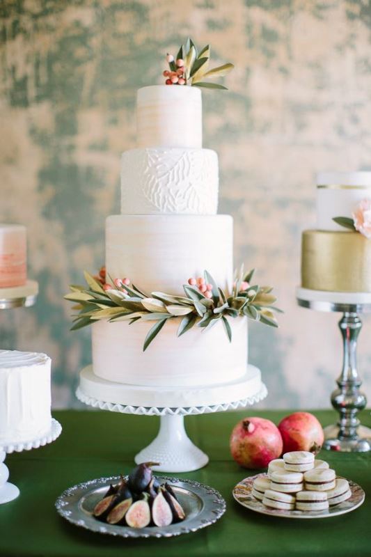 A textural neutral wedding cake with patterns with greenery and bright berries for a Christmas or winter wedding