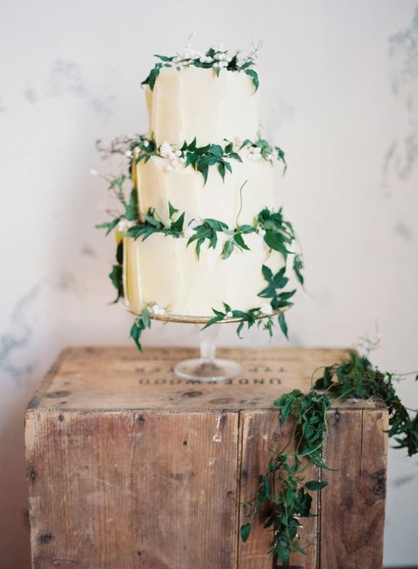 A tan textural wedding cake decorated with foliage and neutral berries is a chic idea for a garden wedding