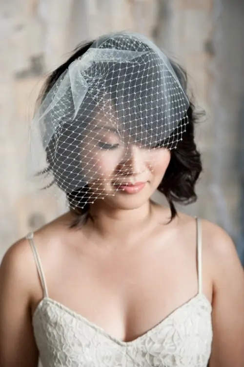 a long black wavy bob with a delicate white birdcage veil is a lovely idea for a modern bride