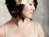 a black wavy bob with side parting and a large blush faux bloom as an accent is a lovely idea for a modern romantic bride