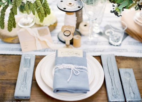 a blue napkin, cutlery holders and a table runner plus greenery make up a chic and romantic tablescape