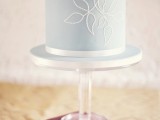 a beautiful powder blue wedding cake with white decor and a large sugar bloom is a tender and sweet idea to try