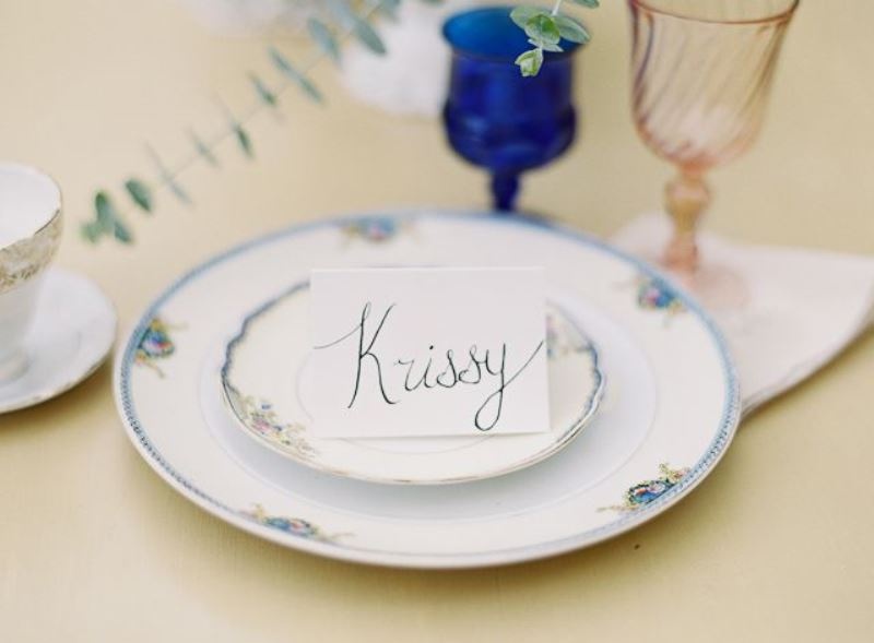 a simple place setting with printed plates and chargers and colored glasses