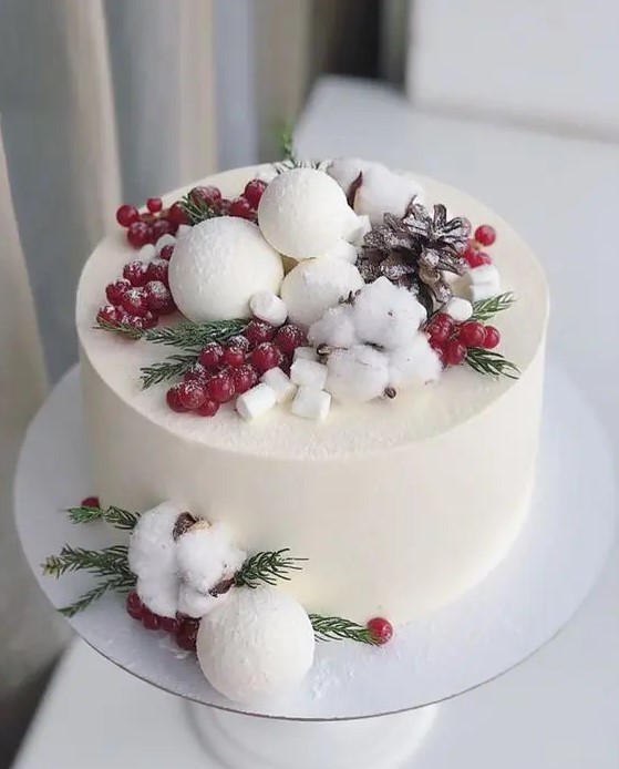 a buttercream wedding cake topped with berries, greenery, snowballs and pinecones plus masrhmallows