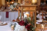 a chic winter wedding centerpiece of white and burgundy blooms, calla lilies, pinecones, evergreens, candles and a candle lantern