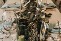 a chic winter wedding table with mint napkins, a eucalyptus runner and candles in green glass candleholders