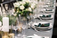 a chic winter wedding table with plaid napkins, white floral centerpieces and greenery, lots of candles and chic cutlery