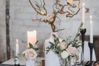 a chic winter wedding tablescape with blush blooms, branches, candles, black candleholders and napkins