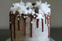a chocolate wedding cake with chocolate dripping, marshmallow snow, edible snowflakes and macarons