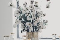 a cozy winter wedding centerpiece of a shiny vase and cotton branches is all you need for a homey feel