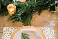a festive winter wedding tablescape with evergreens, candles, polka dot placemats and gold chargers