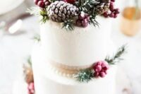 a frosted wedding cake with berries, fir, pinecones and ribbons is a stylish wedding dessert to rock
