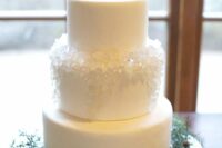 a frozen white wedding cake with edible ice on one of the tiers is a gorgeous idea for a winter wedding