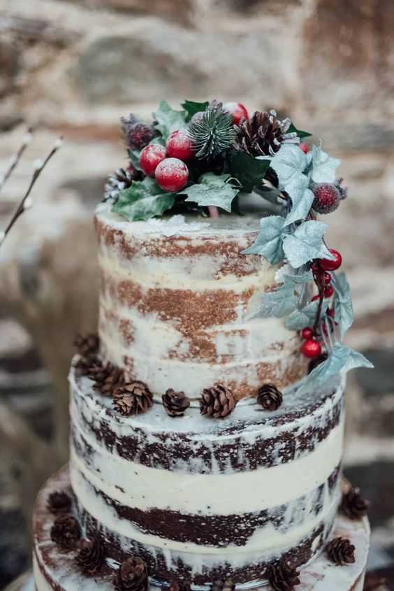 a naked two color wedding cake decorated with greenery, evergreens, pinecones, berries is a lovely idea for a winter wedding