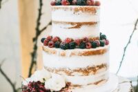 a naked wedding cake topped with fresh berries and white blooms is a stylish idea for many weddings