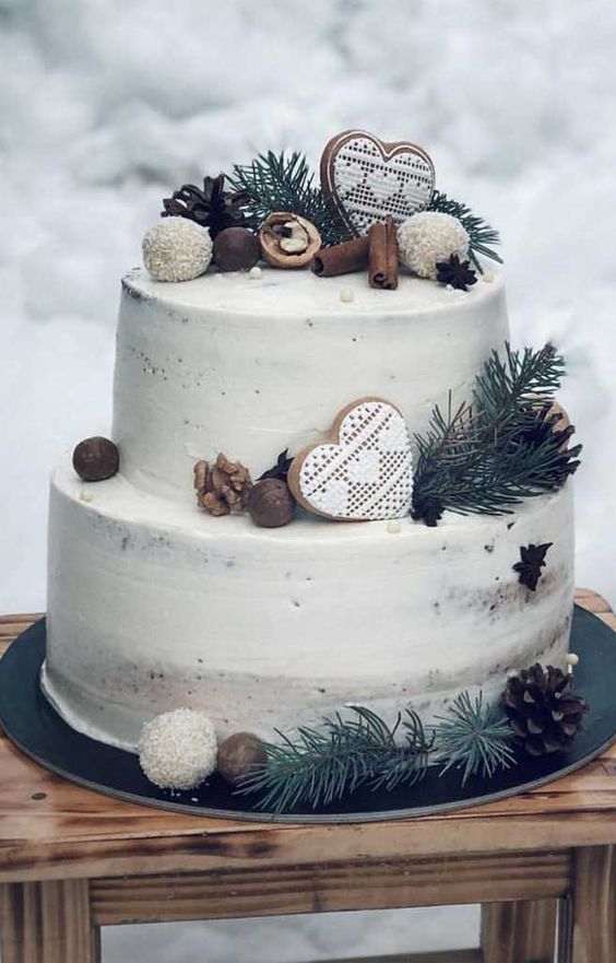 a naked wedding cake topped with nuts, evergreens, glazed heart-shaped cookies, cinnamon and candies is a chic and delicious idea for winter