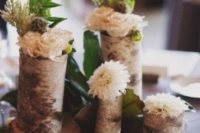 a rustic winter wedding centerpiece of wood slices, tree stumps, candles, pebbles and some greenery and blooms