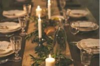 a rustic winter wedding tablescape with a fabric runner, greenery, candles and some wood slices