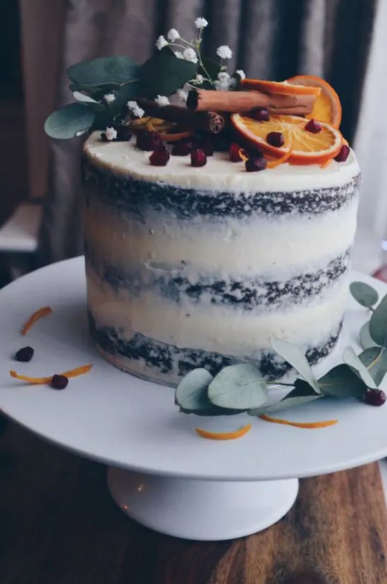a semi naked gingerbread wedding cake with pomegranate seeds, citrus, cinnamon and flowers