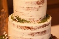a simple semi naked wedding cake topped with pinecones, ferns and berries for a rustic winter wedding