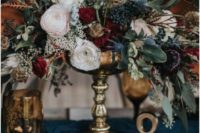 a stylish and textural winter floral centerpiece of burgundy, blush blooms, thistles, privet berries and foliage