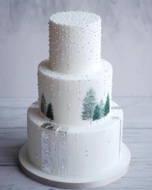 a white wedding cake with silver leaf ribbons, tiny polka dots and painted Christmas trees is a great idea for winter