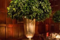an elegant winter wedding centerpiece of a metallic urn with much greenery in it is a stylish idea