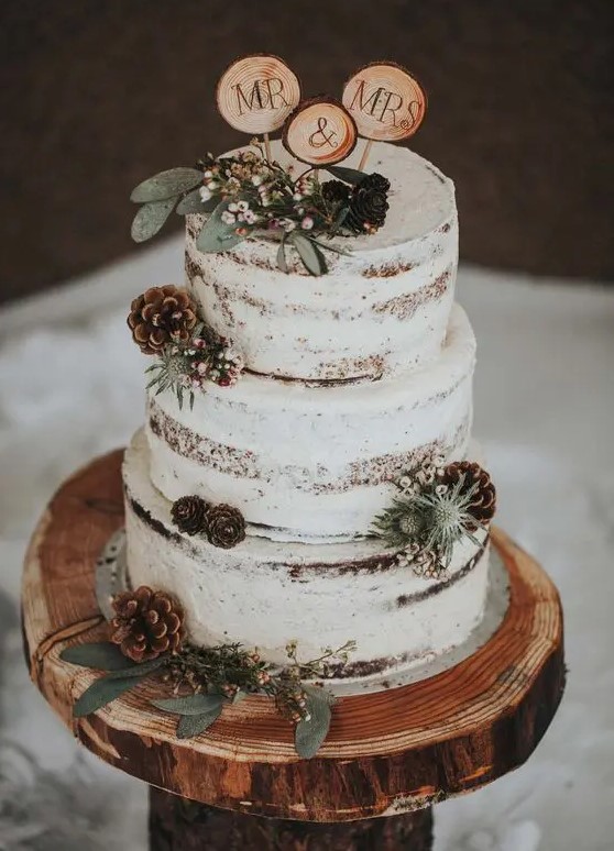 cake toppers made of wood slices and with greneery and berries added are a great idea for a rustic or woodland wedding
