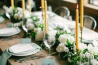 a beautiful wedding table setting with mint napkins and cards, greenery and white blooms and yellow candles