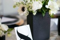 a black textural vase with lush blooms and a black and white table number
