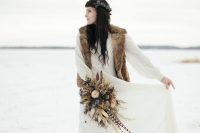 a boho winter bridal look with an A-line wedding dress with long sleeves and a beige faux fur wiastcoat plus boots