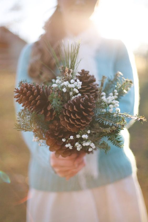 a bouquet made of large pinecones, evergreens and baby's breath for a rustic winter bride