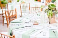 a bright summer wedding table with mint napkins, a box centerpiece with succulents and feathers plus neutrals