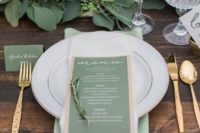 a bright summer wedding tablescape with a greenery runner, a green menu, mint napkins and gold cutlery